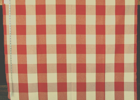 A red and cream gingham checkered fabric laid flat, with a measuring tape visible along the left edge.