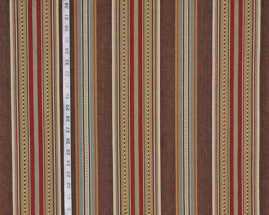 A close-up of a striped fabric pattern with vertical bands in brown, rust red, beige, and muted blue, with a white measuring tape running down the center to indicate scale.