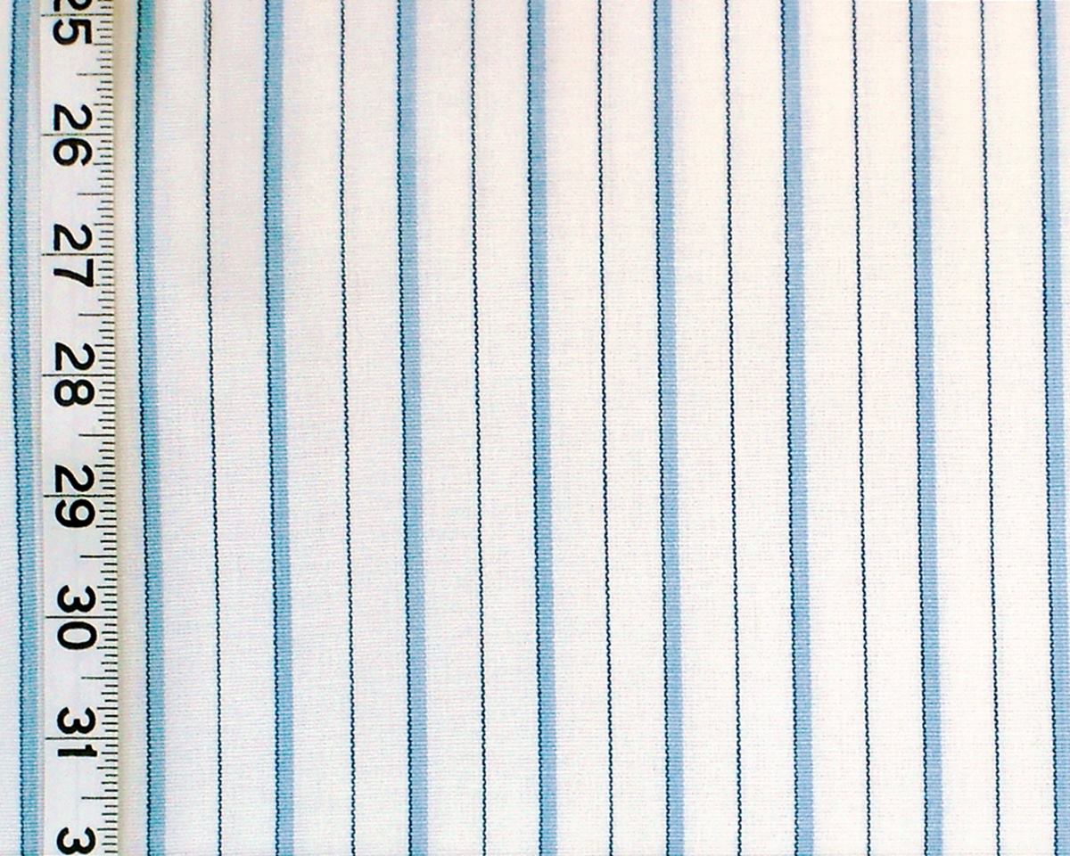A close-up of striped fabric with vertical light blue and white stripes, shown next to a ruler for scale.