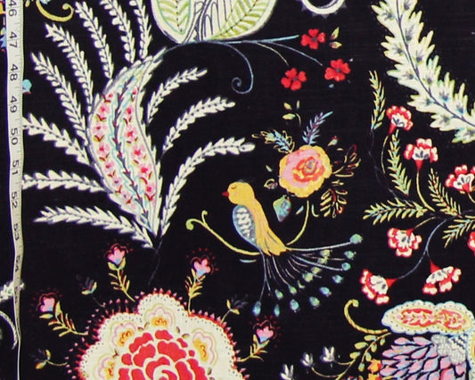 Black fabric with a colorful embroidered floral and bird pattern, shown close up with a measuring tape visible along the left edge.