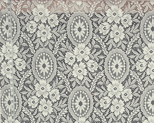 A close-up of a lace fabric with an intricate floral and medallion pattern in cream and gray.