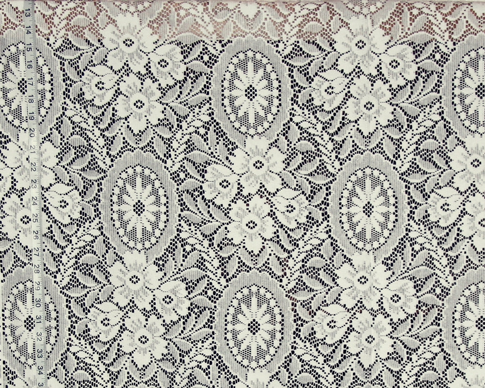 A close-up of a lace fabric with an intricate floral and medallion pattern in cream and gray.