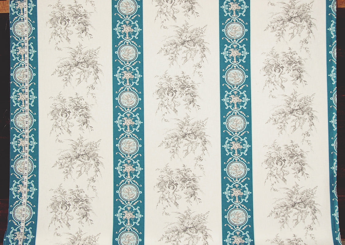 A close-up of a patterned fabric or wallpaper featuring vertical stripes with teal ornamental borders and a repeating beige floral toile motif on an off-white background.