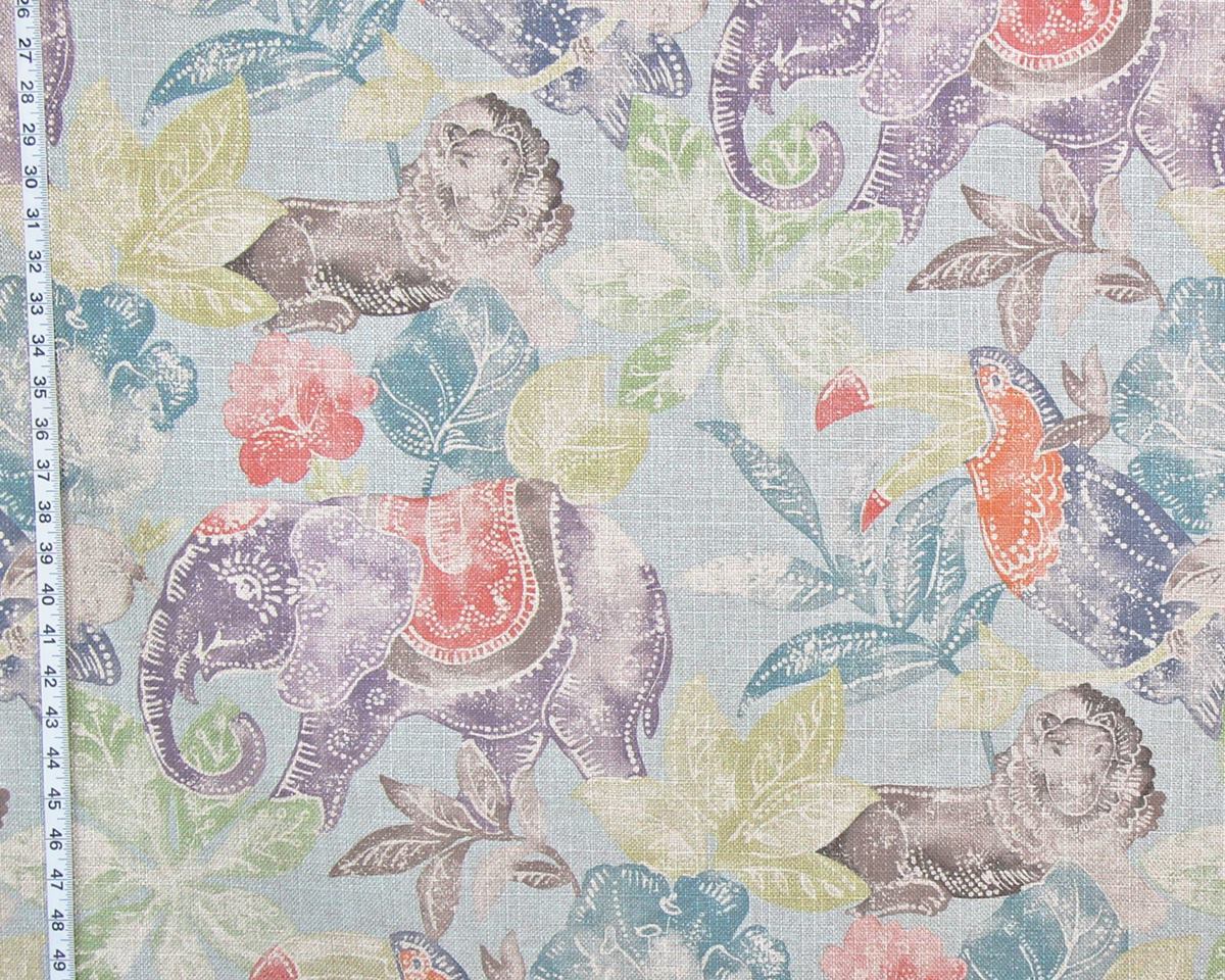 A close-up of patterned fabric featuring purple elephants, blue and teal leaves, and coral flowers on a pale blue background, with a measuring tape visible along the left edge.