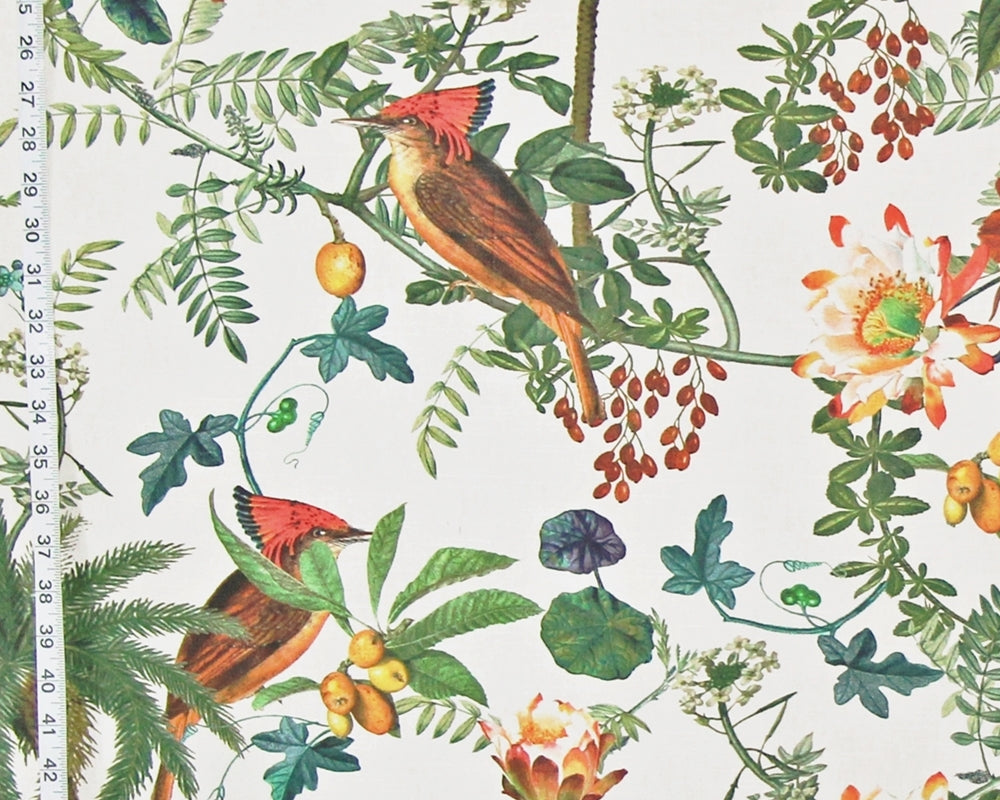 A close-up of a botanical and bird print fabric featuring two red-crowned woodpeckers among green leaves, yellow berries, and white flowers on an off-white background, with a measuring tape visible along the left edge.