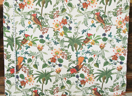 A close-up of a fabric or wallpaper pattern featuring tropical birds, palm trees, and flowers on a white background, photographed flat against a dark wood surface.