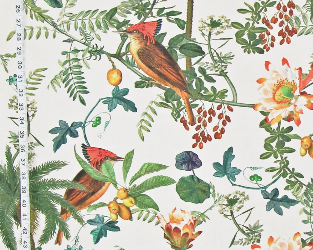 A close-up of a botanical fabric pattern featuring two red-crowned birds perched among green leaves, yellow berries, and orange flowers on an off-white background, with a measuring tape visible along the left edge.