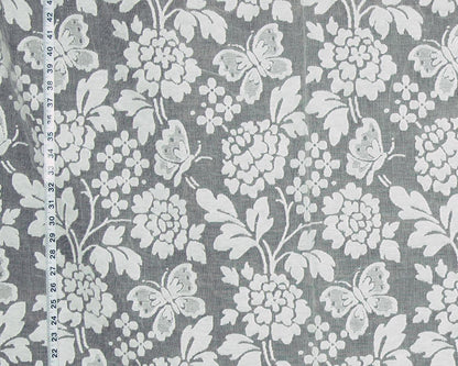 Gray fabric with a white floral and butterfly pattern, shown with a measuring tape along the left edge for scale.