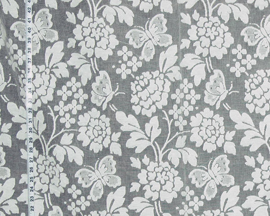 Gray fabric with a white floral and butterfly pattern, shown with a measuring tape along the left edge for scale.