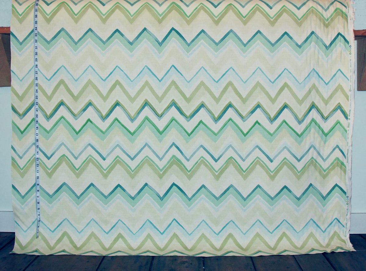 Chevron patterned fabric with green and blue zigzag design on a wooden surface