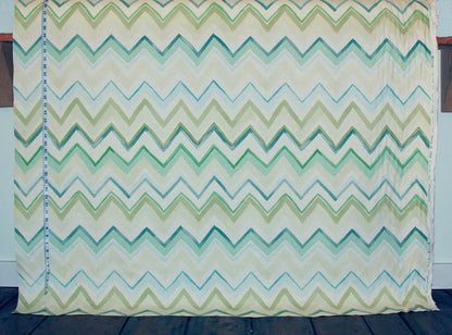 Chevron patterned fabric with green and blue zigzag design on a wooden surface