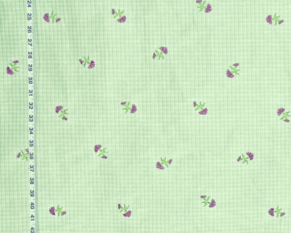 Light green gingham fabric with a repeating pattern of small purple flowers and green leaves, shown with a black ruler on the left edge for scale.
