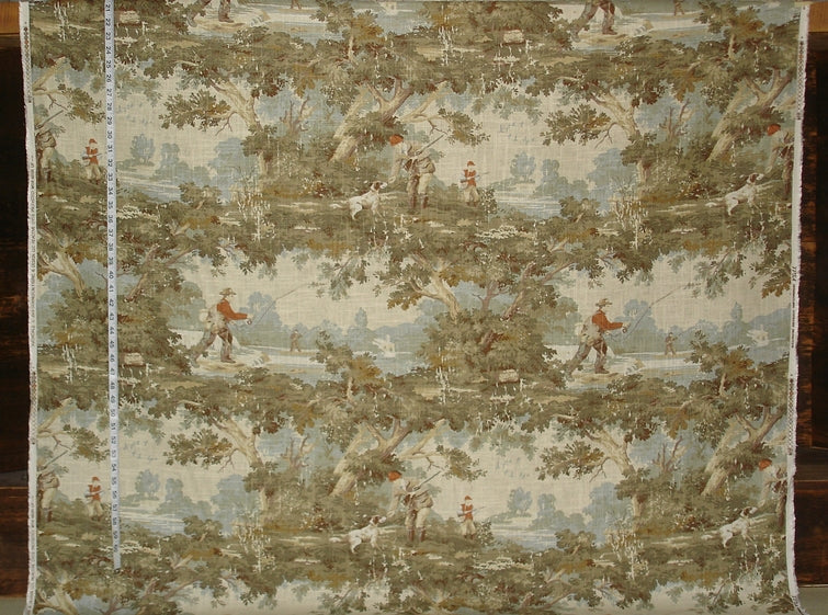 Textile with landscape design featuring figures and trees, displayed on a wooden surface.