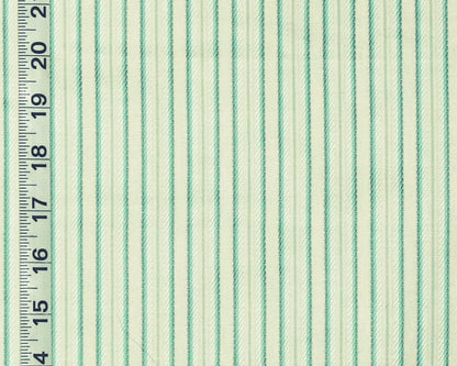 A close-up of striped fabric with alternating mint green and off-white vertical stripes, shown next to a black inch ruler for scale.