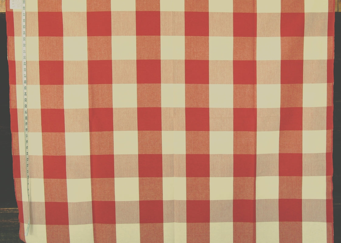 A red and cream gingham checkered fabric laid flat, with a measuring tape visible along the left edge.