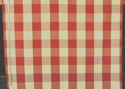 A red and cream gingham checkered fabric laid flat, with a measuring tape visible along the left edge.