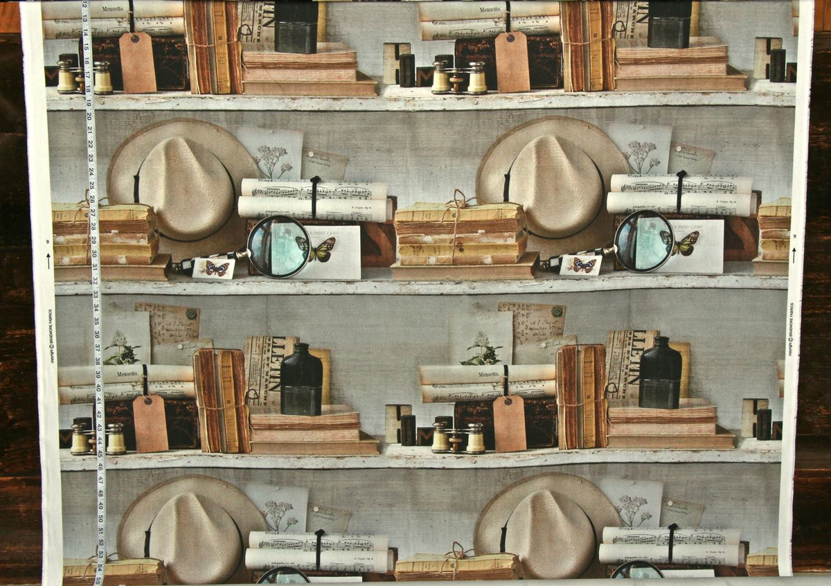 A repeating pattern of vintage bookshelves filled with books, hats, bottles, and small accessories, shown as a fabric or wallpaper design with a measuring tape along the left edge.