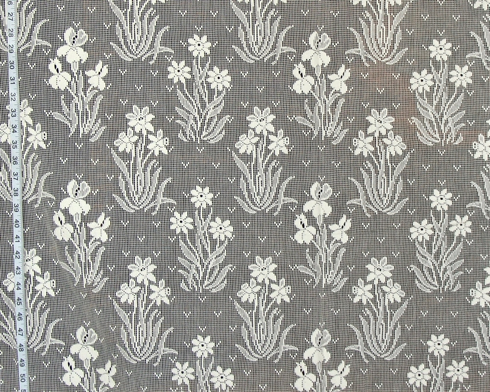 Gray and white floral patterned fabric with a repeating iris-like motif, shown close up with a measuring tape along the left edge.