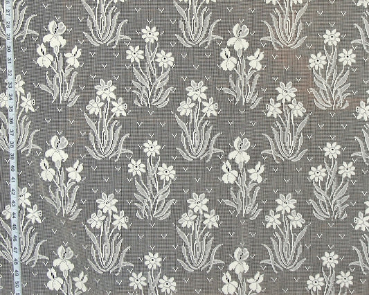 Gray and white floral patterned fabric with a repeating iris-like motif, shown close up with a measuring tape along the left edge.