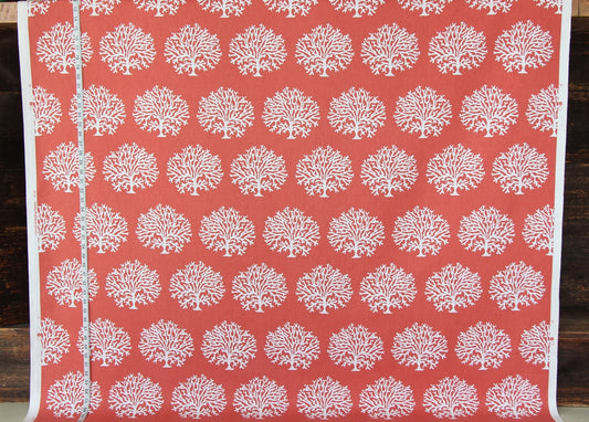 A close-up of a coral red fabric or wallpaper featuring a repeating white tree-of-life pattern, with a white border and a silver seam line visible on the left.