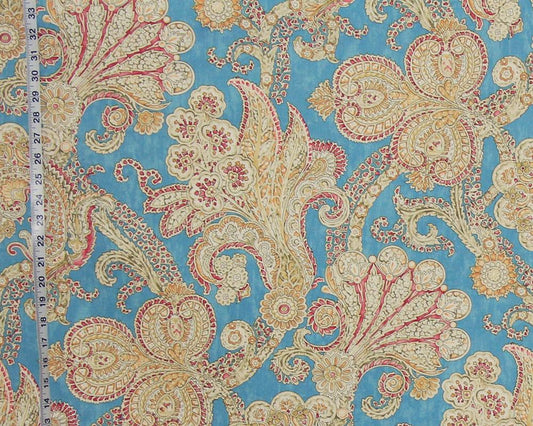 Decorative fabric with paisley pattern on a blue background, measured by a tape measure.