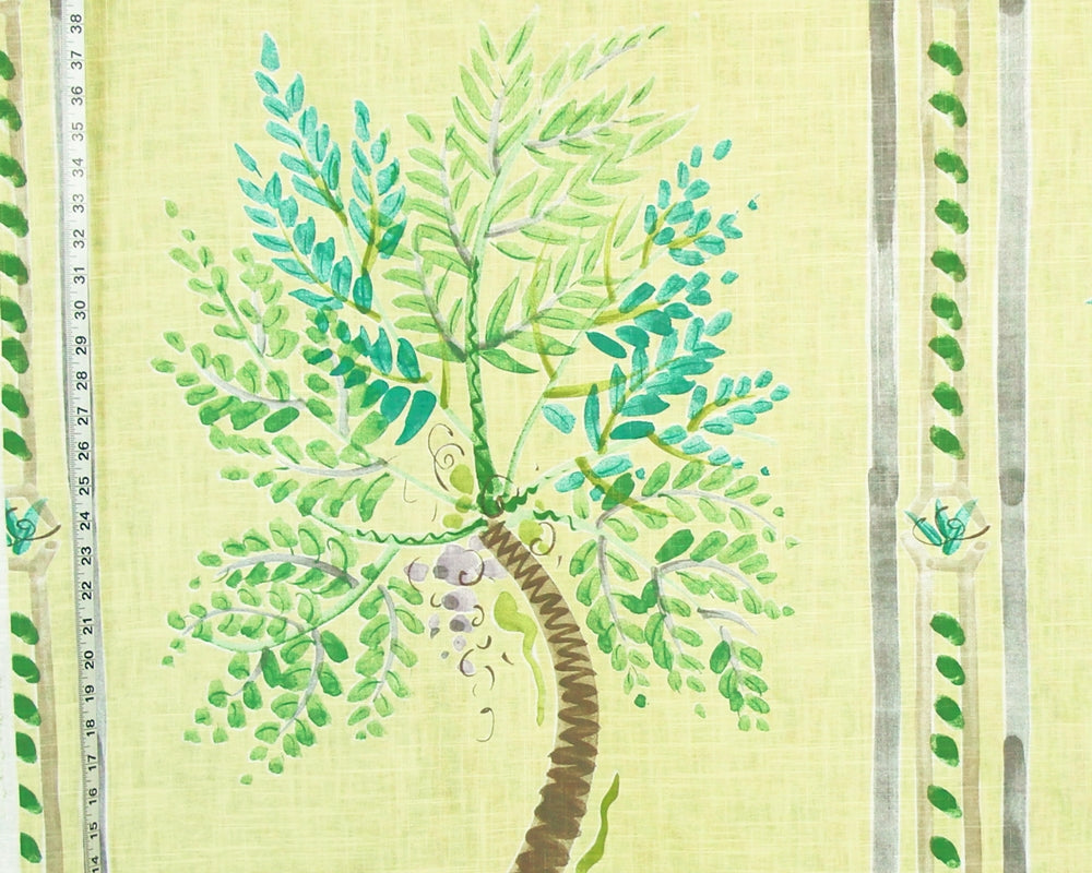 A close-up of a fabric or wallpaper pattern featuring a painted green palm tree on a pale yellow background, with vertical decorative stripes and small leaf motifs along the sides.