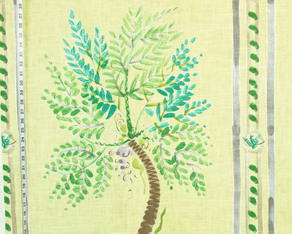 A close-up of a fabric or wallpaper pattern featuring a painted green palm tree on a pale yellow background, with vertical decorative stripes and small leaf motifs along the sides.