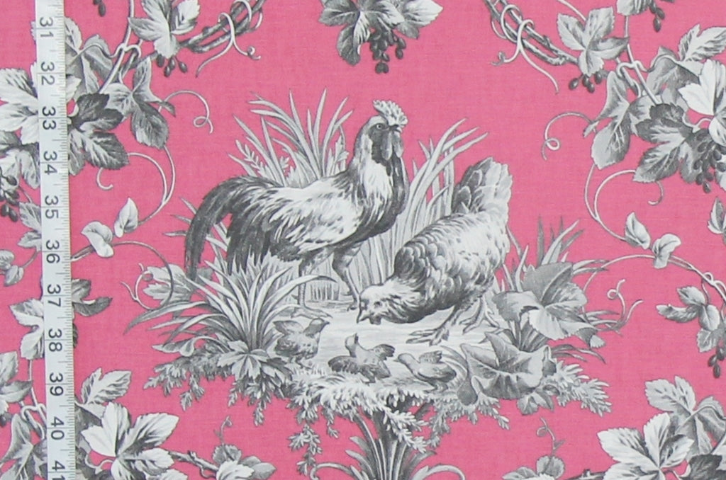 Pink fabric with a classic French Toile pattern featuring gray and black illustrations of a rooster, hen, ducks, and climbing vines, shown with a white ruler on the left edge for scale.