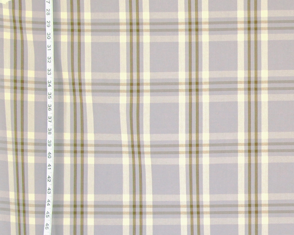 A close-up of a plaid fabric pattern with a light gray base, cream stripes, and muted olive green lines, with a vertical ruler on the left side showing measurement markings.