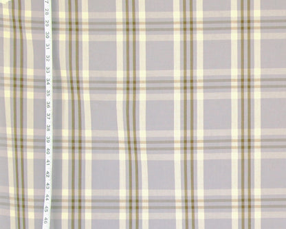 A close-up of a plaid fabric pattern with a light gray base, cream stripes, and muted olive green lines, with a vertical ruler on the left side showing measurement markings.