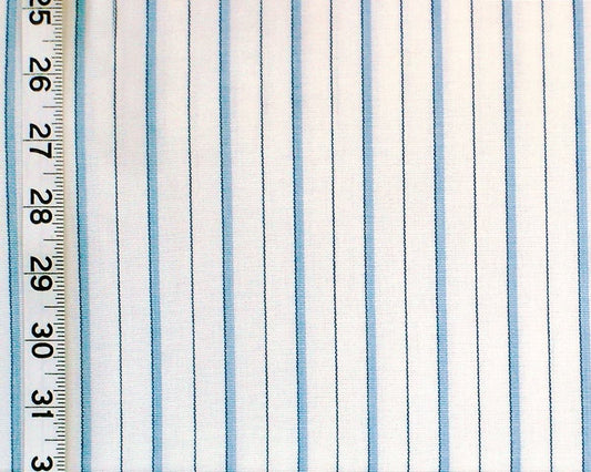A close-up of striped fabric with vertical light blue and white stripes, shown next to a ruler for scale.