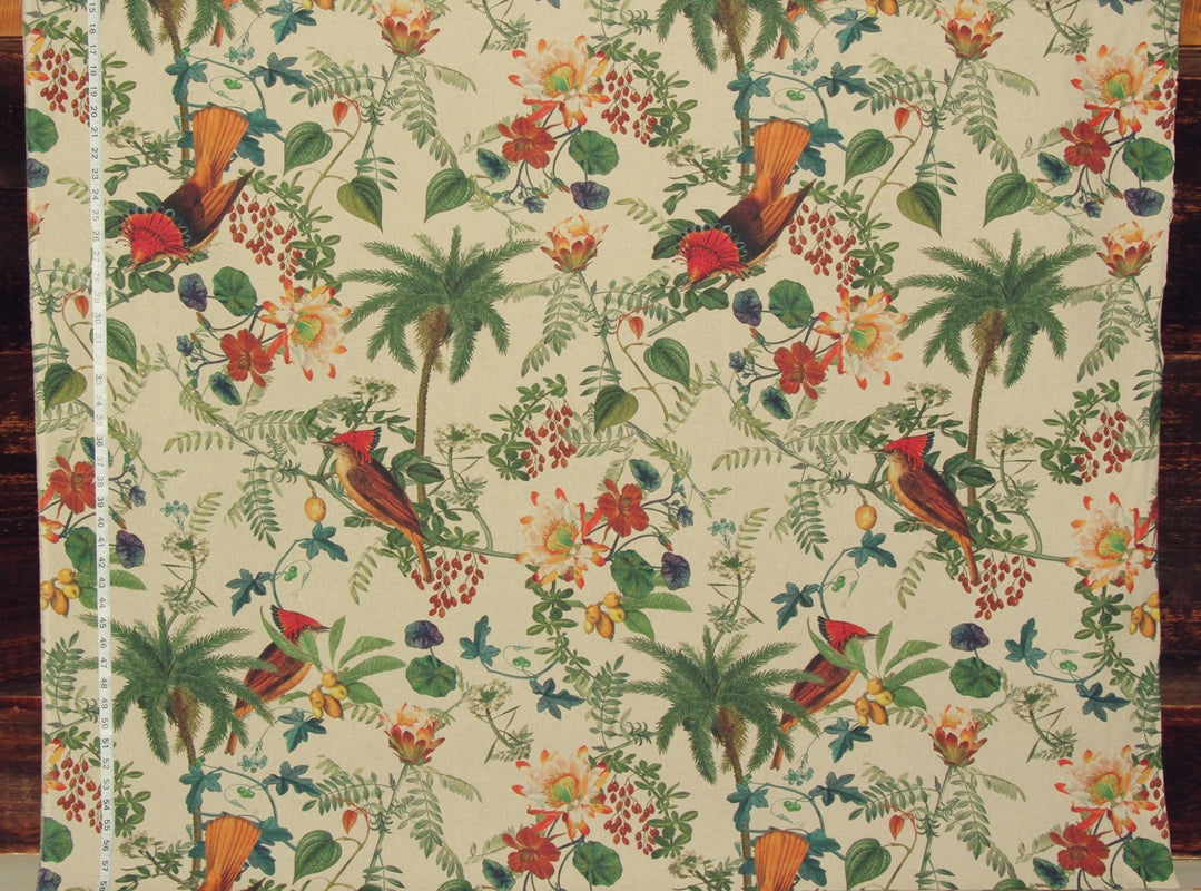 A close-up of a tropical fabric featuring a repeating pattern of red and orange birds, green palm trees, and orange flowers on a cream background, with a white measuring tape visible along the left edge.