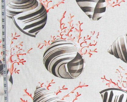 A close-up of a fabric pattern featuring black and white striped seashells and coral in red-orange on a light beige background, with a measuring ruler visible along the left edge.