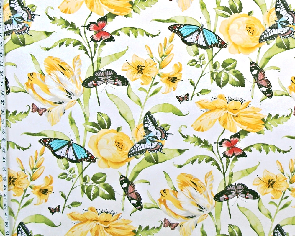 A close-up of a fabric or wallpaper pattern featuring yellow flowers, green leaves, and colorful butterflies on a white background, with a measuring ruler visible along the left edge.