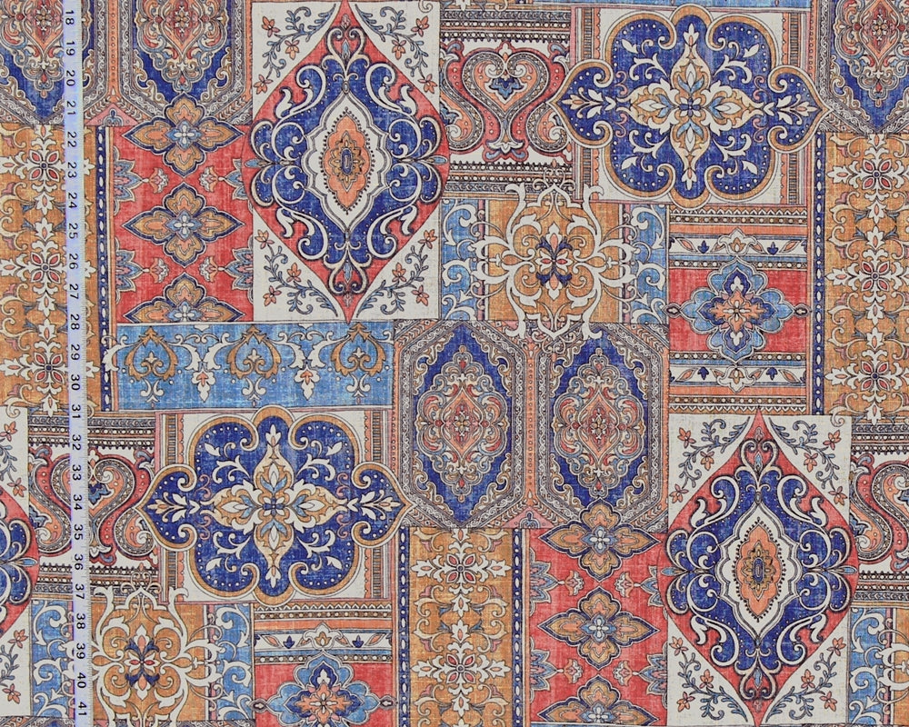 A close-up of a fabric or wallpaper pattern featuring a patchwork of traditional oriental and Persian-style motifs in blue, red, beige, and orange, with a white ruler on the left side showing the 12-inch scale.