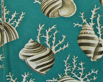 A close-up of a teal fabric with a repeating pattern of striped seashells and white coral branches, with a measuring tape visible along the left edge.