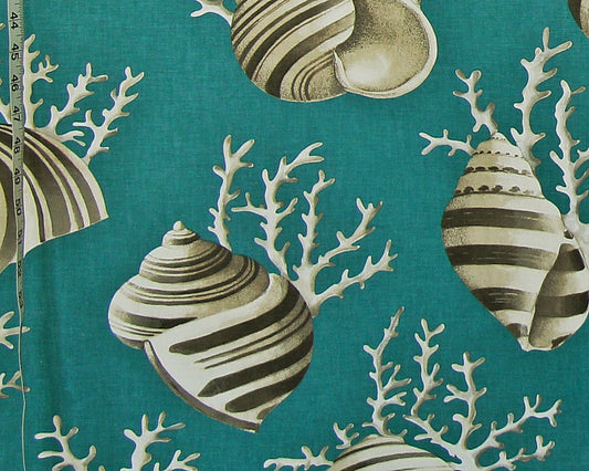 A close-up of a teal fabric with a repeating pattern of striped seashells and white coral branches, with a measuring tape visible along the left edge.