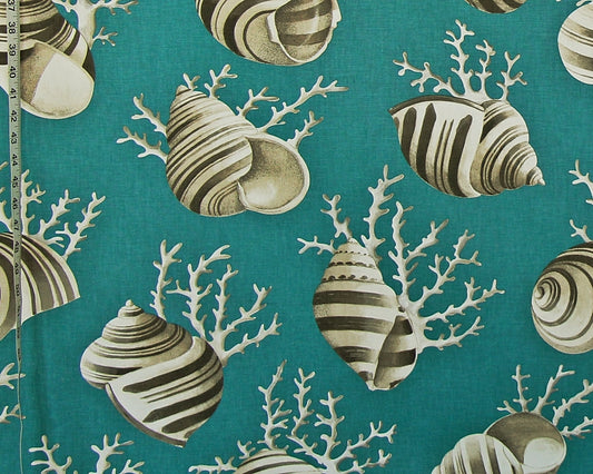 A close-up of a teal fabric with a repeating pattern of striped seashells and white coral, with a measuring tape visible along the left edge.