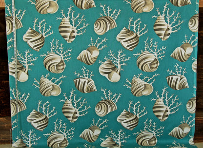 A close-up of a fabric or wallpaper pattern featuring striped seashells and white coral branches on a teal background, with a measuring tape visible along the left edge.