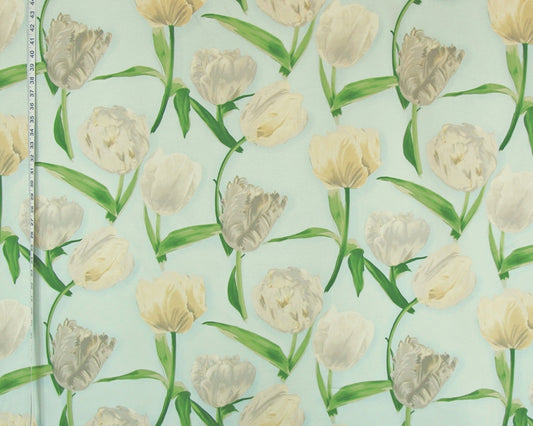 A close-up of a fabric or wallpaper pattern featuring watercolor-style tulips in cream, beige, and light gray with green stems on a pale mint-green background. A ruler is visible along the left edge for scale.