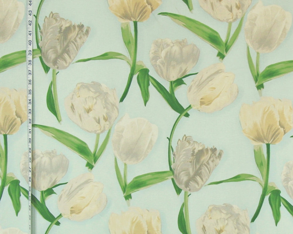 A close-up of a floral patterned surface featuring cream and off-white tulips with green stems and leaves on a pale mint background, with a measuring tape visible along the left edge.