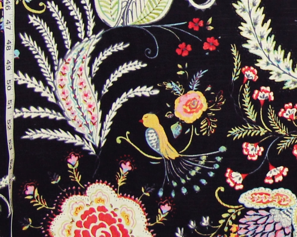 Black fabric with a colorful embroidered floral and bird pattern, shown close up with a measuring tape visible along the left edge.