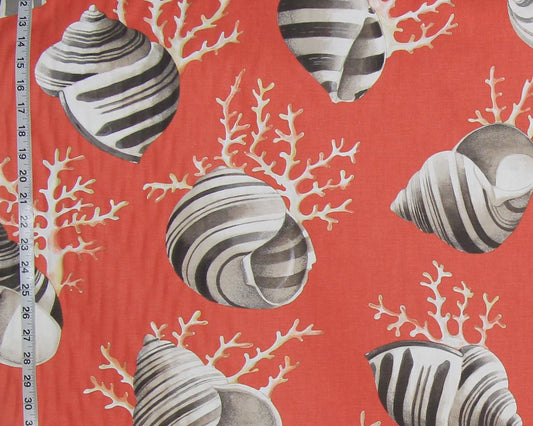 Red fabric with a repeating pattern of striped seashells and white coral branches, shown with a measuring tape along the left edge.