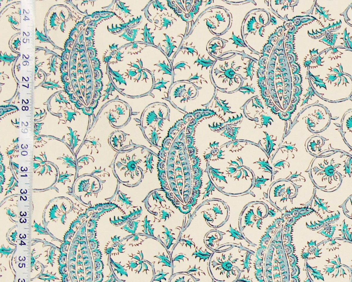 Patterned fabric with turquoise paisley design on a beige background, measured against a ruler.