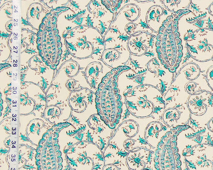 Patterned fabric with turquoise paisley design on a beige background, measured against a ruler.
