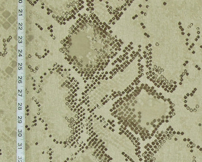 A close-up of a snakeskin-patterned fabric with a beige background and dark brown spots, featuring a white ruler on the left side for scale.